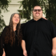 Jacob, a young man with glasses stands outside with his mother, Marilyn. Her arm is around his shoulder, they are smiling.