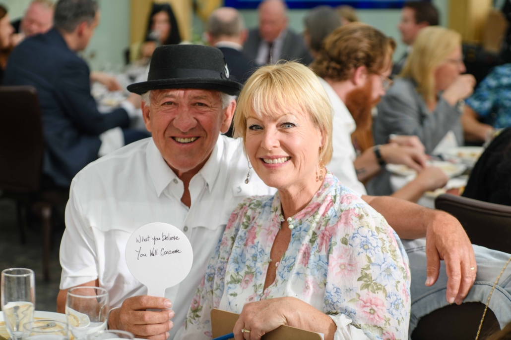 A man and a woman smile as they sit at a table.