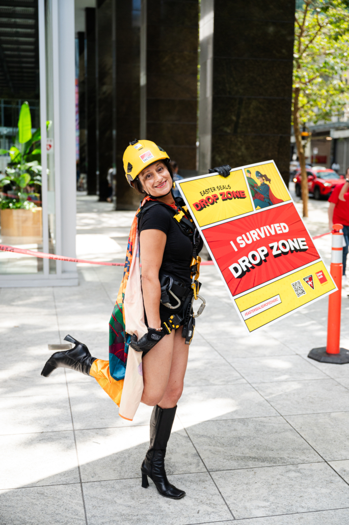 One drop zone rappeller at the bottom of a building holding a sign that says "I surivived drop zone"